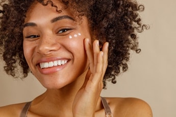 Jovem aplica creme de hidratação facial em sua pele facial
