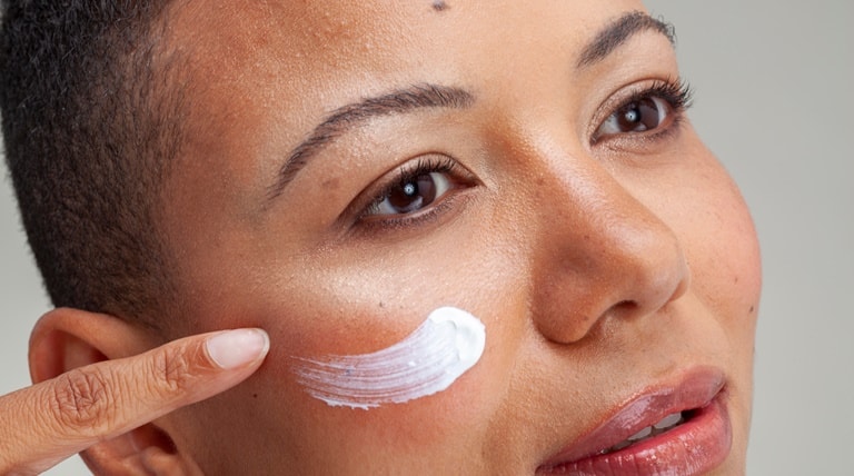 Mulher aplica o hidratante para o rosto antes do protetor solar facial