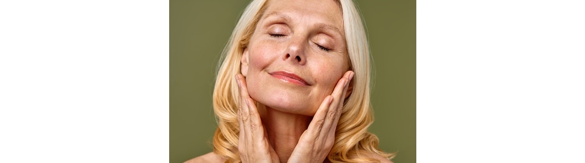 Senhora caucasiana utiliza creme hidratante para pele madura, mantendo a pele facial macia