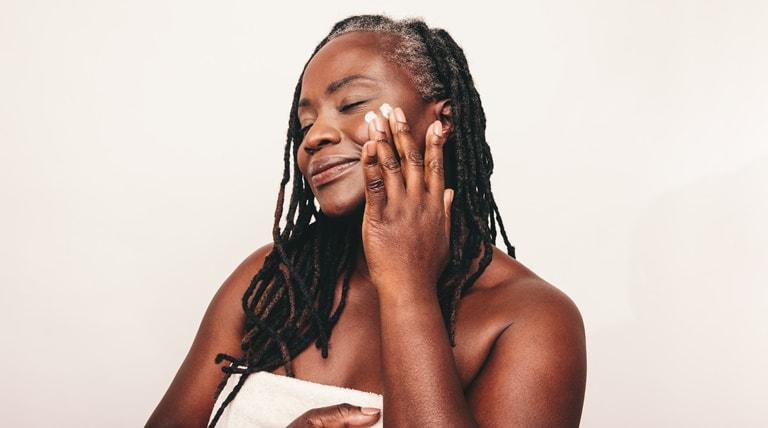 Senhora utiliza creme hidratante em sua pele madura, mantendo a pele hidratada, macia e elástica.