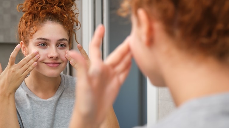 Jovem garota realizando esfoliação facial com esfoliante químico para ter uma pele macia