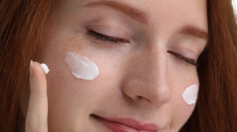 Jovem aplica hidratante para o rosto para manter a pele macia