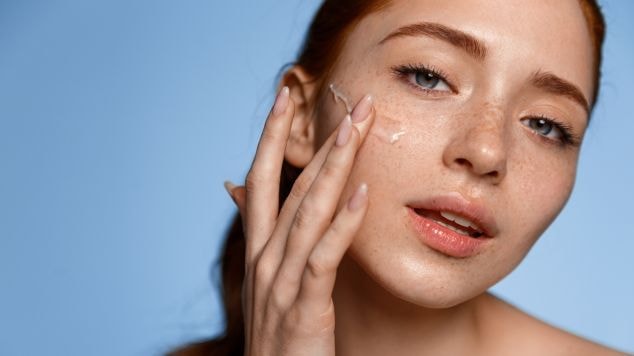 Jovem aplicando hidratante facial do seu potinho de hidratante