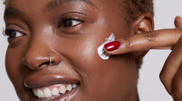 Jovem mulher negra utiliza um hidratante para pele oleosa de textura leve