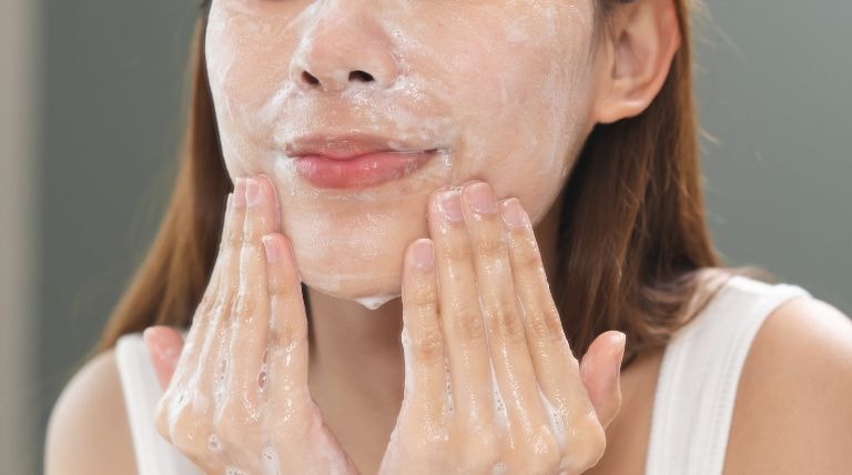 Jovem garota realiza a limpeza facial com um sabonete para acne
