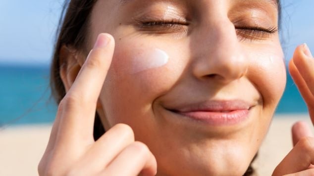 Mulher sorridente ao aplicar o filtro solar