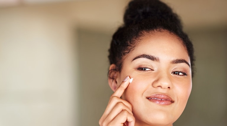 Jovem aplica o protetor solar para o rosto em sua pele facial