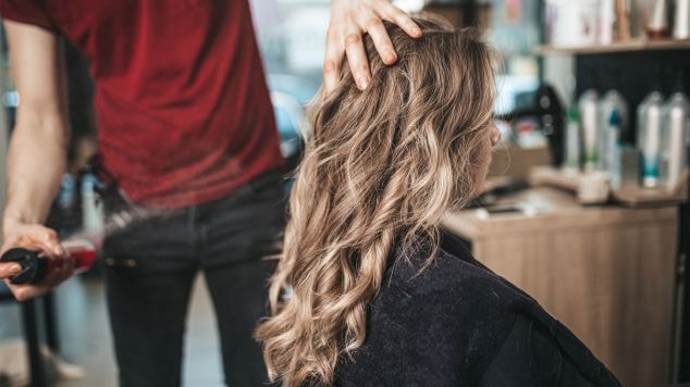 profissional cabeleireiro aplica o tom loiro manteiga no cabelo de sua cliente.