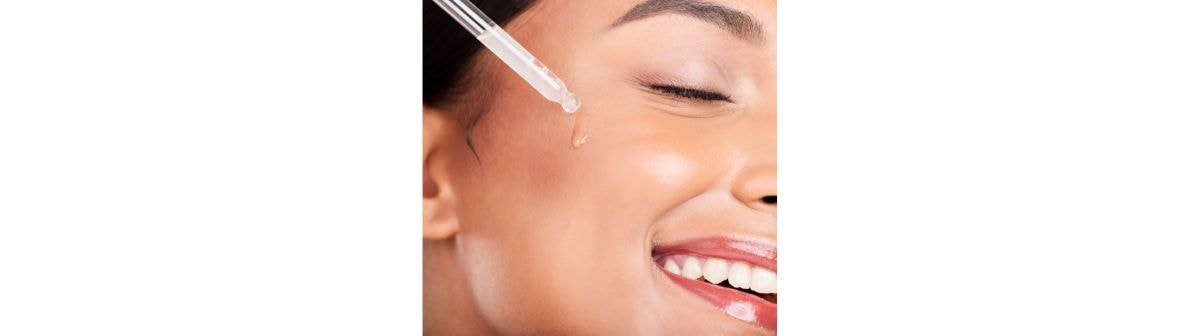 Mulher sorridente aplica um sérum facial com ácido hialurônico em sua pele do rosto