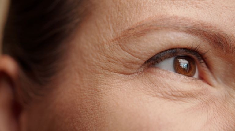 Detalhes da pele ao redor dos olhos de uma mulher com rugas e linhas finas na pele do rosto