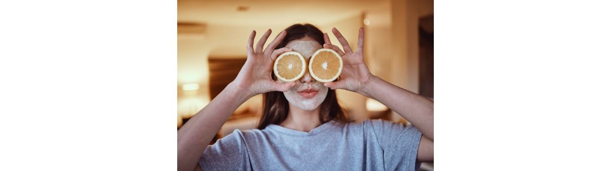 Jovem com duas rodelas de laranja fresca e vibrante em frente aos olhos.