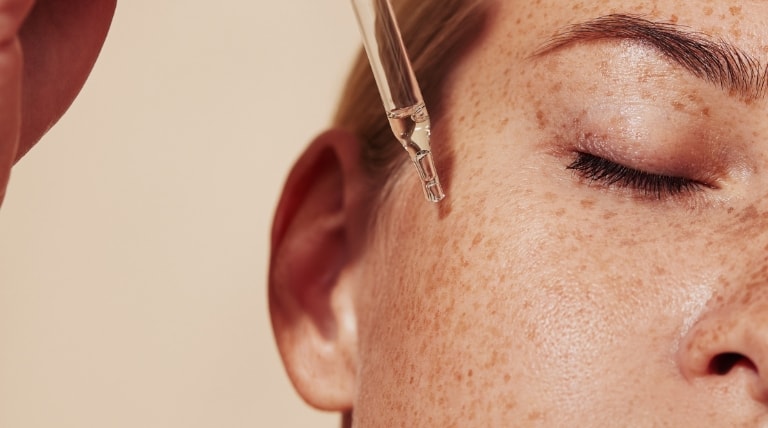 Jovem aplica produtos de skincare para cuidar de sua pele do rosto.