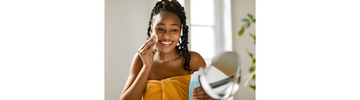  Mulher negra e sorridente aplica o tônico para o rosto em sua pele facial como parte de sua rotina de skincare