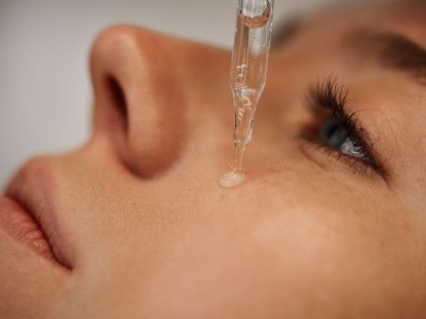  Foto de uma mulher aplicando um sérum facial com ácido hialurônico para o rosto.