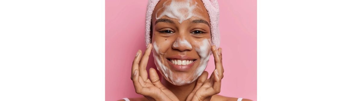 Jovem garota negra realiza a limpeza facial em sua rotina diária de skincare.