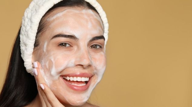 Mulher fazendo limpeza da pele com espuma do sabonete. 