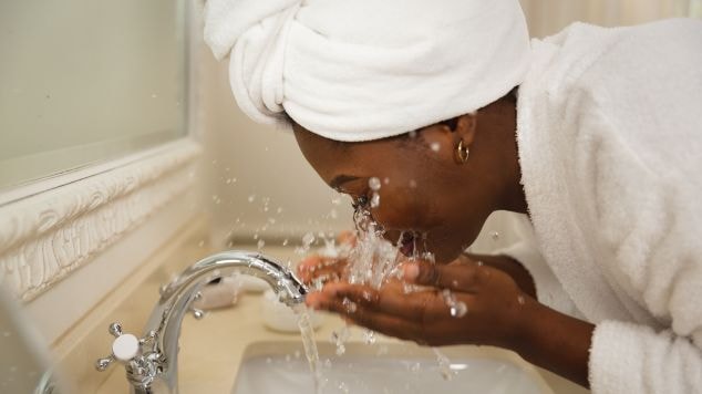 Mulher negra realizando a limpeza facial com um sabonete para o rosto oleoso.