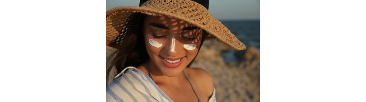 Jovem mulher na praia aplica um protetor solar com toque seco em seu rosto.