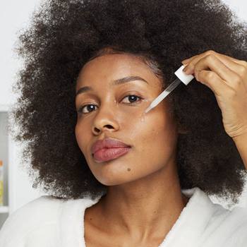 Imagem de uma modelo negra aplicando o Sérum Booster em seu rosto | Garnier